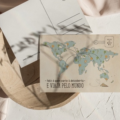 Dois postais com mapa e texto sobre mesa branca e prato de madeira