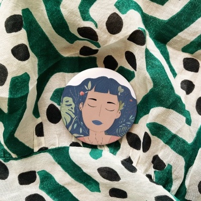 Botão com ilustração de mulher sobre tecido estampado.