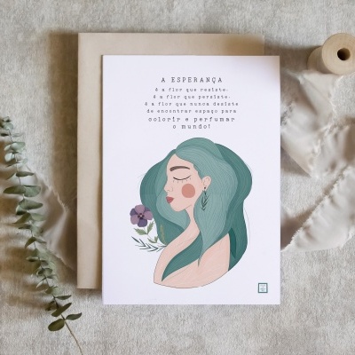 Cartão ilustrado com mulher e texto A ESPERANÇA sobre superfície clara com envelope, ramo seco e fita