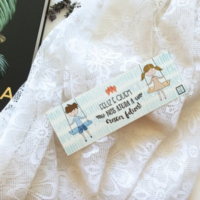 Etiqueta de papel para roupas infantil sobre tecido rendado branco ao lado de livro