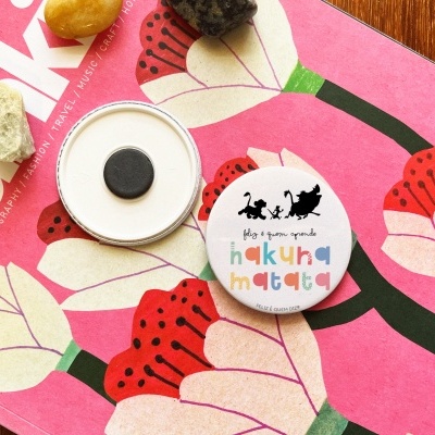 Botão com ilustração de gatos sobre revista com flores e cristais