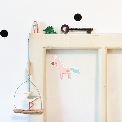 Porta branca antiga com decoração artesanal pendurada e desenhos na parede
