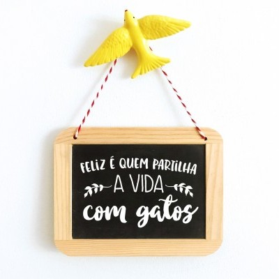Placa decorativa com frase sobre gatos e pássaro amarelo