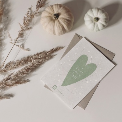 Dois abóboras decorativas, planta seca e cartão com coração verde e texto