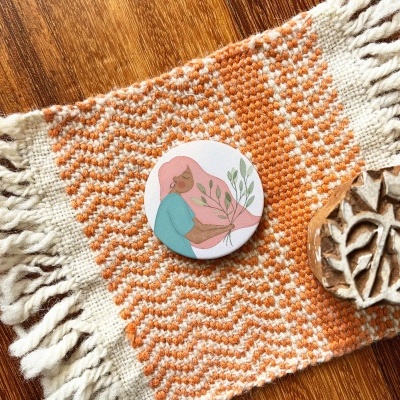 tecido decorativo laranja e branco com dois pequenos objetos circulares sobre superfície de madeira