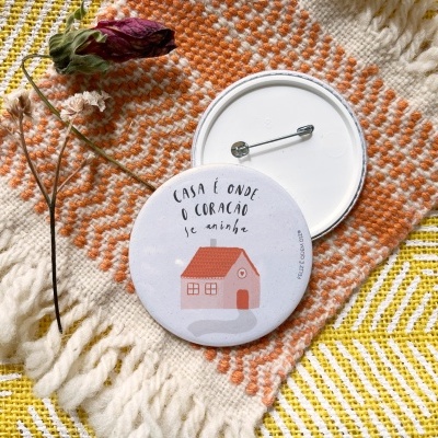 Dois bottons redondos com casa e texto colocados sobre tecido colorido com ramo seco