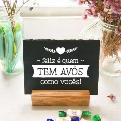 Cartão preto com mensagem em branco entre frascos de vidro com flores secas e bolinhas coloridas sobre mesa branca