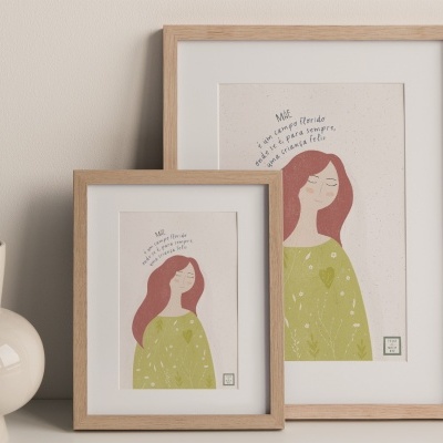 duas molduras de madeira com ilustrações de mulheres, ao lado de um vaso cerâmico creme