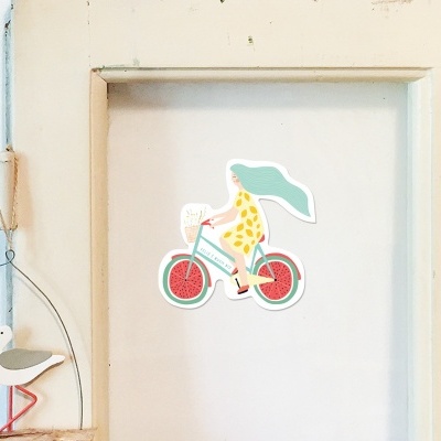 Autocolante de pessoa em bicicleta colado numa porta clara e objeto decorativo pendurado com gaivota em madeira