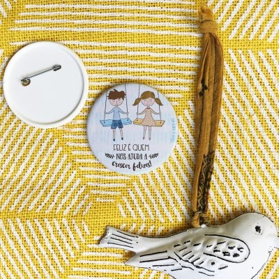 Botão redondo com ilustração de crianças e texto em fundo amarelo com pássaro decorativo.