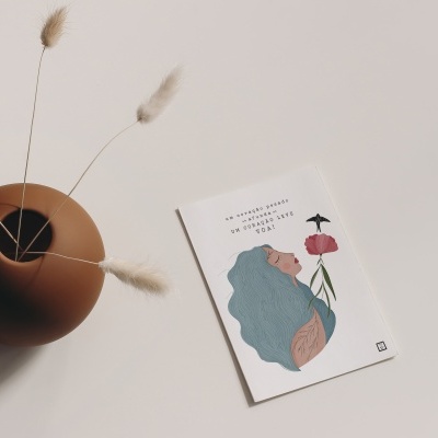 Vaso terra com flores secas e cartão ilustrado com texto em português