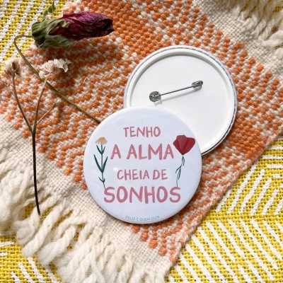Bottons redondos com texto sobre tecido artesanal colorido e ramo seco