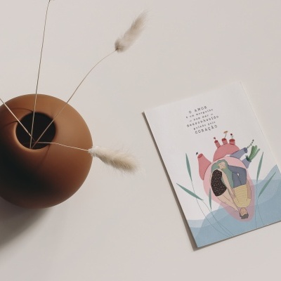 Vaso castanho com flores secas e cartão colorido com texto em português