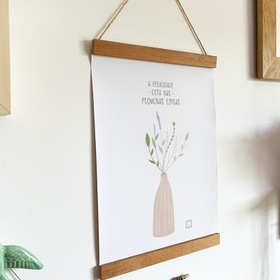 Poster decorativo branco com ilustração de vaso e flores e texto, pendurado com madeira, paredes e objetos decorativos ao redor