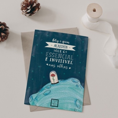 Cartão temático com ilustração da Terra e texto em português, colocado sobre envelope castanho, com pinhões e fita branca ao lado.