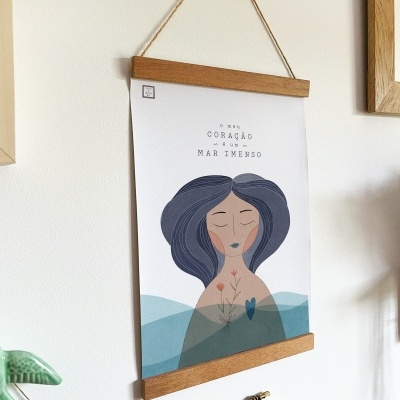 Pôster decorativo com ilustração de mulher e texto em português pendurado na parede com moldura de madeira