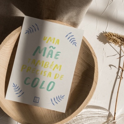 Cartão com texto colorido sobre prato de madeira e pano bege com ramo seco