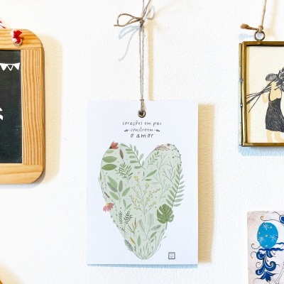 Decorações penduradas numa parede branca com quadros e cartões ilustrados coloridos