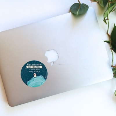 Computador portátil prateado com autocolante azul e planta verde