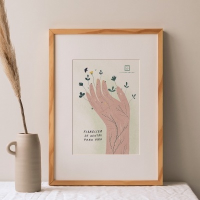 quadro com ilustração de uma mão e texto, ao lado vaso de cerâmica com folha seca
