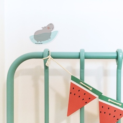 Cabeceira de cama verde com varal decorativo de melancia e autocolante de hipopótamo na parede