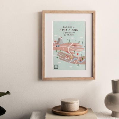 quadro em moldura de madeira com arte colorida e texto, vaso branco decorativo, planta com folha verde, objeto sobre mesa clara