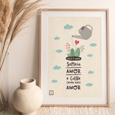 Pôster decorativo com regador e planta, texto em português, moldura de madeira sobre mesa com vaso e plantas secas