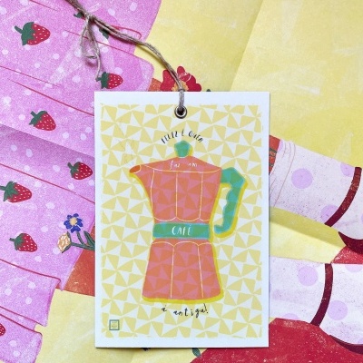 Etiqueta com desenho de cafeteira rosa e verde pendurada em tecidos coloridos com padrões diversos