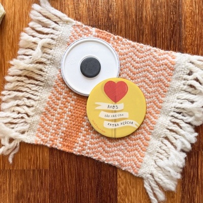 Tapete pequeno laranja e branco com franjas, pedras e objetos redondos em cima