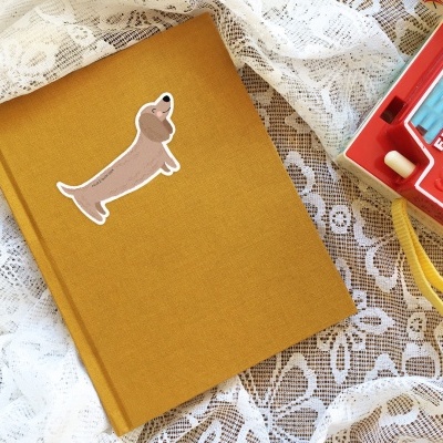 Caderno amarelo com autocolante de cão e câmara fotográfica vermelha