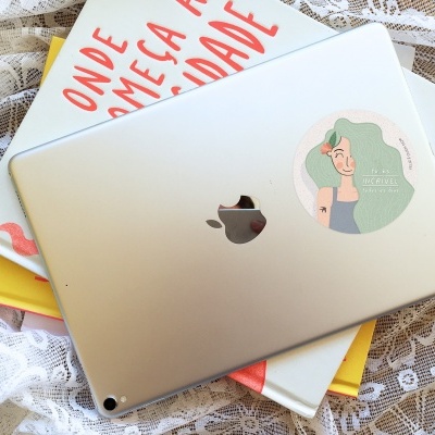 Tablet Apple cinzento com autocolante sobre livros e tecido rendado