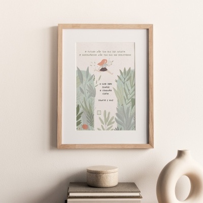 Quadro com moldura de madeira e ilustração de folhas, pássaro e texto em português numa parede branca