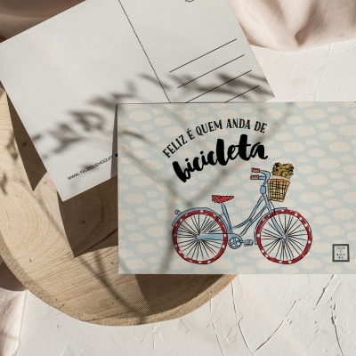Postal com ilustração de bicicleta e texto em português