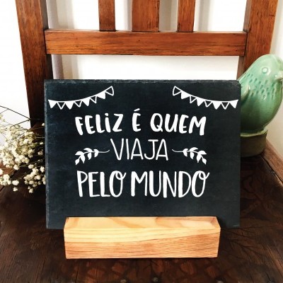 Placa decorativa preta com texto branco sobre base de madeira e cadeira de madeira escura