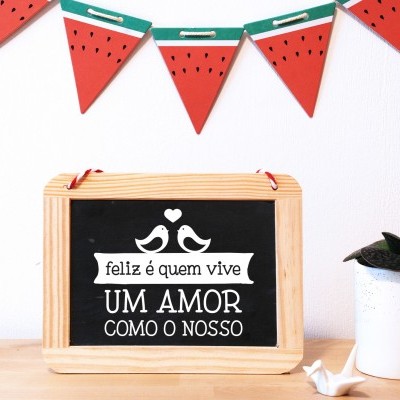 Placa decorativa de madeira com texto em português, guirlanda temática vermelha e planta no vaso branco