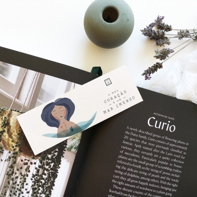 Livro aberto, cartão ilustrado, vaso, flores secas e tecido branco rendado