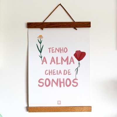 Panfleto decorativo com flores e texto TENHO A ALMA CHEIA DE SONHOS pendurado numa parede