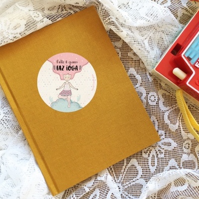 Livro amarelo com etiqueta circular e câmara Fisher-Price vermelha sobre tecido rendado branco