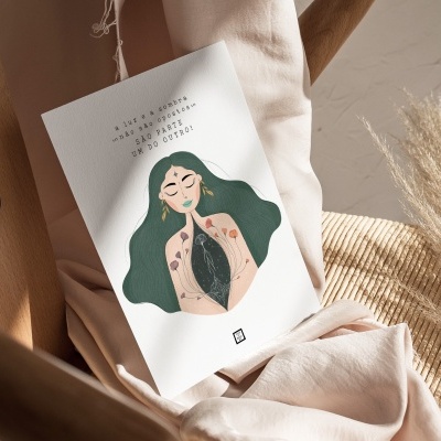 Cartaz decorativo com ilustração feminina e texto em português pousado em cadeira de madeira com tecido e folhas secas.