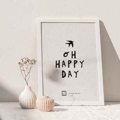 Quadro branco com texto 'OH HAPPY DAY' e dois vasos cerâmicos em superfície branca