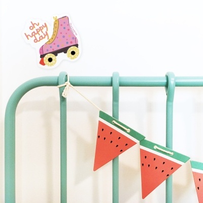 Cabeceira de cama verde claro com bandeirolas e autocolante colorido na parede.