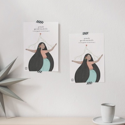 Dois cartazes com ilustração de mulher, uma estrela decorativa cinzenta e vaso branco num ambiente minimalista