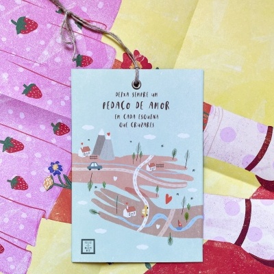 Cartão com ilustração e texto em português sobre fundo com tecido rosa com morangos e amarelo com detalhes vermelhos