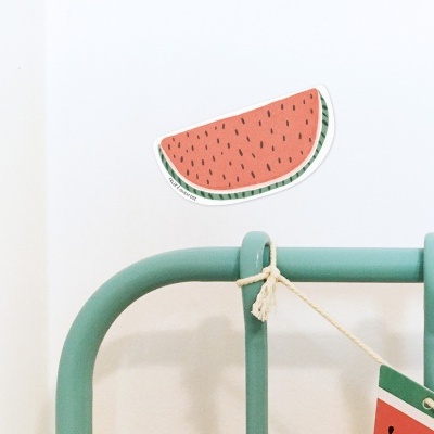 Cabeceira de cama verde com decoração de melancia na parede e saco pendurado