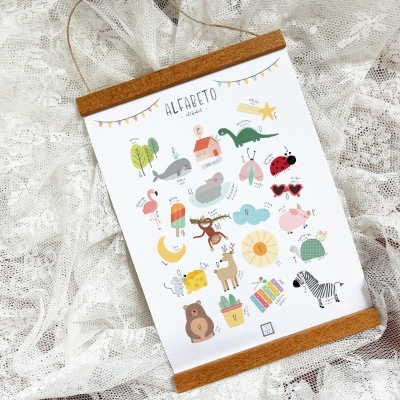 Poster infantil do alfabeto com figuras coloridas, moldura de madeira, sobre tecido rendado branco.