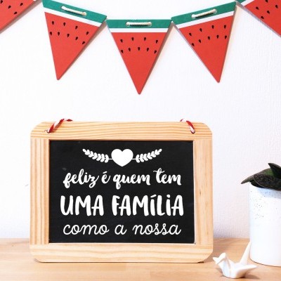 Quadro decorativo com texto sobre família, vaso com planta e guirlanda de melancias