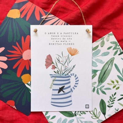 Três cartazes com temas florais e folhas sobre tecido vermelho