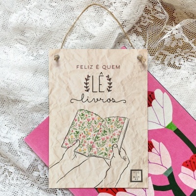 Cartaz decorativo com ilustração de mãos segurando livro floral e texto em português.