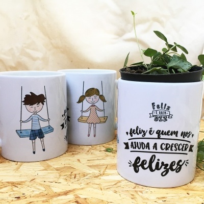 Canecas e vaso branco com plantinha e texto em superfície de madeira