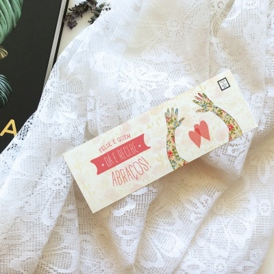 Toalha branca rendada com cartão colorido e parte de revista preta com texto amarelo